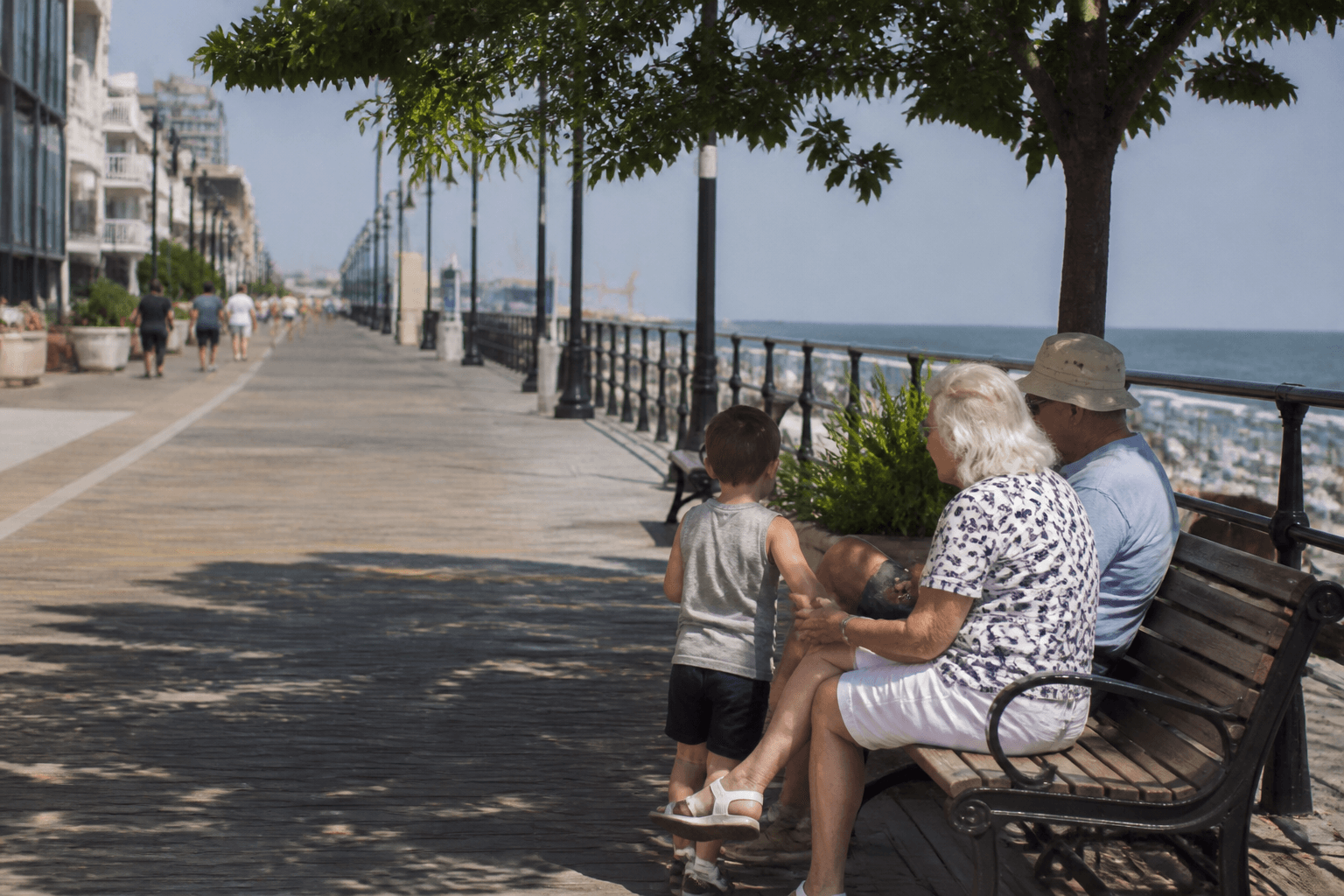 Boardwalk rest-bench family pace in Ocean City: shady pause with the boards stretching ahead — Beach Blog photo, Ocean City, Maryland