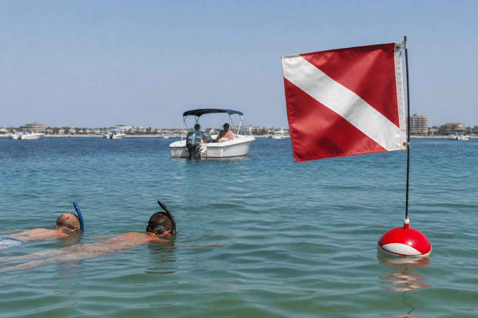 Alpha dive flag on a boat stern with swimmers in Assawoman Bay and the Ocean City skyline behind them