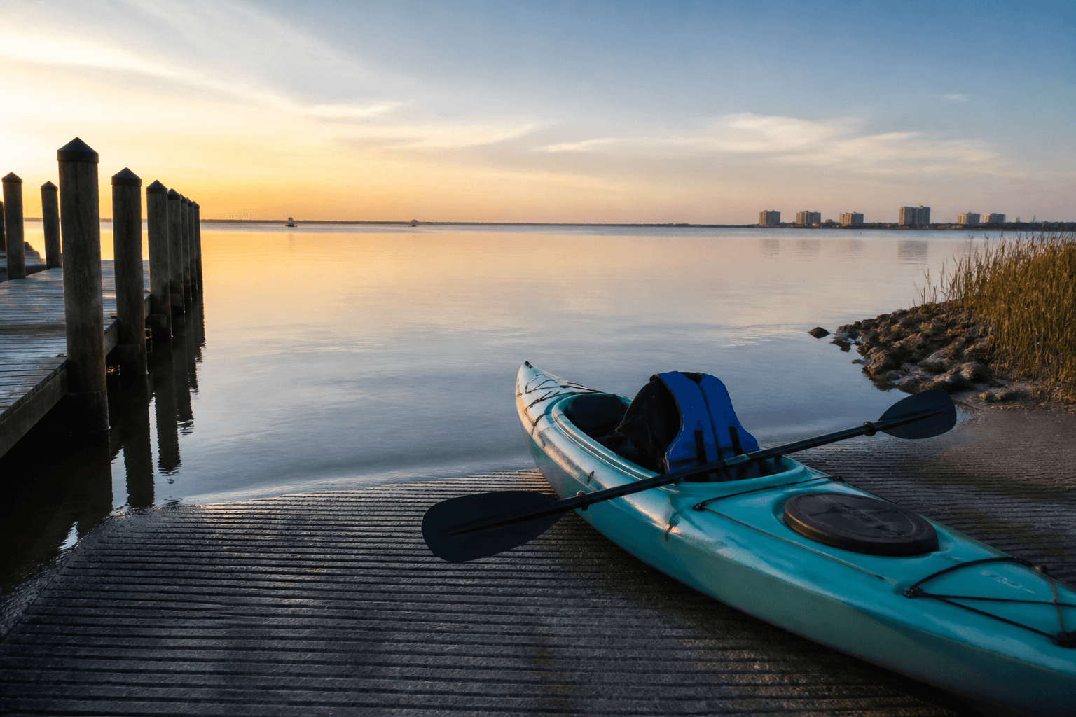 Kayaker staging a PFD and paddle at a calm Assawoman Bay launch near Ocean City Maryland