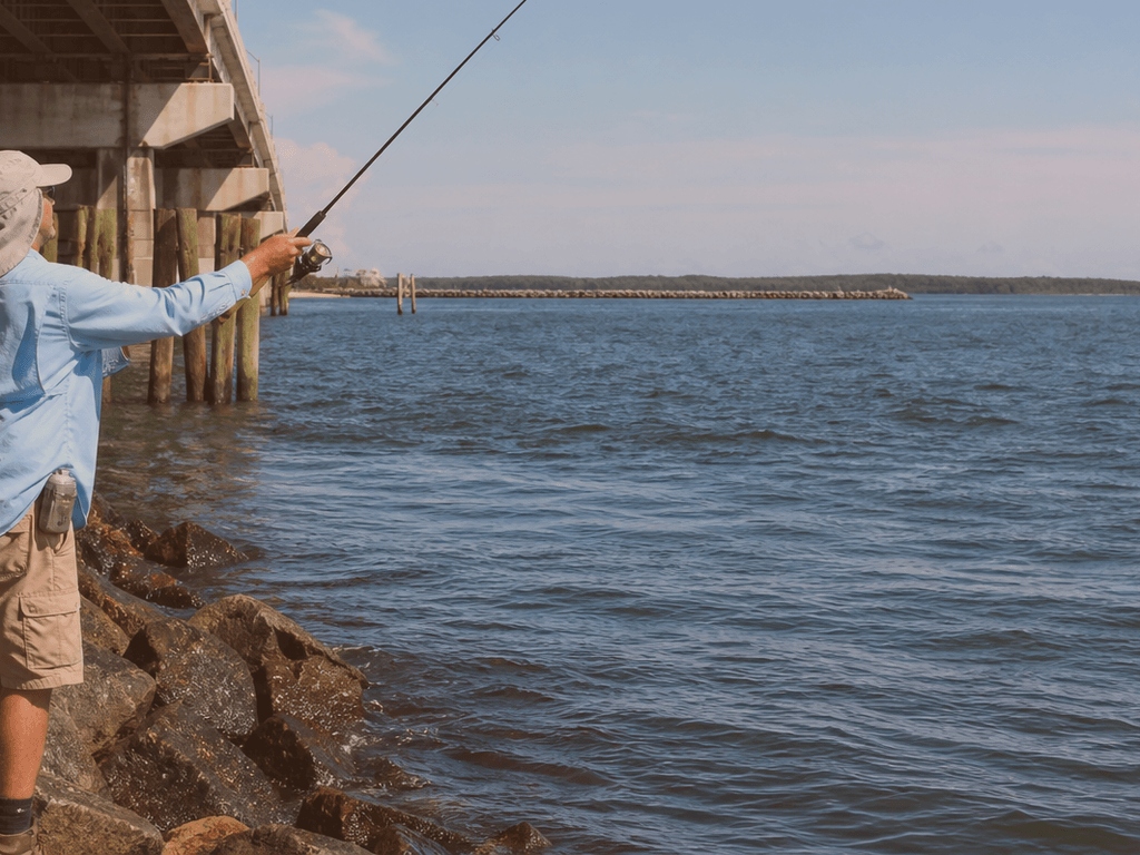 Fishing tackle and rod staged near Ocean City inlet jetty rocks with tide moving