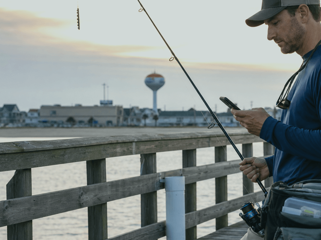 Angler showing digital fishing license on phone at Ocean City pier entrance