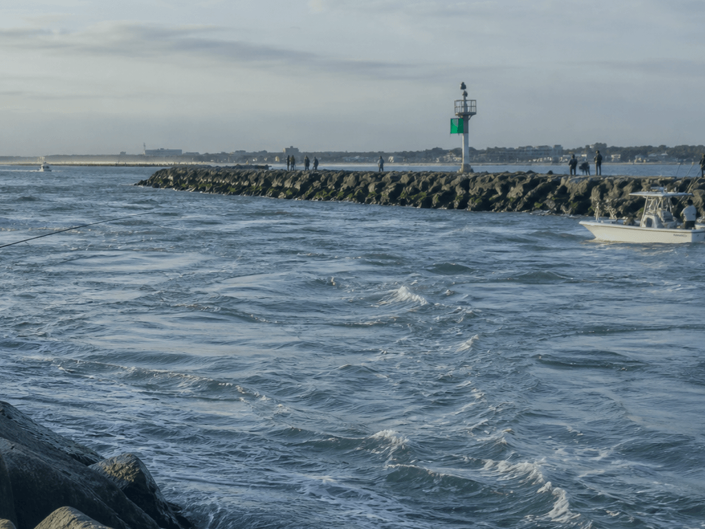 Tide chart app open beside fishing rod at Ocean City inlet