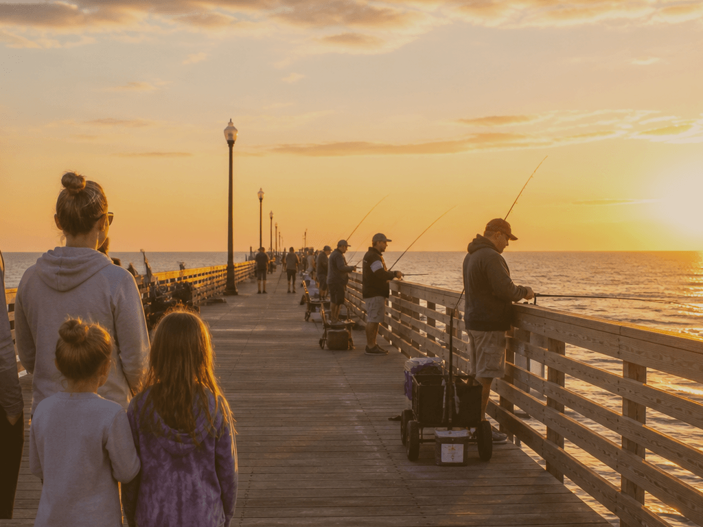 Silhouettes on Ocean City pier at golden hour with fishing lines in the foreground