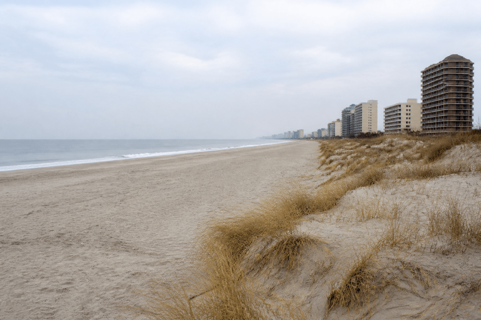 Quiet winter beach in Ocean City Maryland: empty sand, gray-blue sky, and off-season calm — Beach Blog photo
