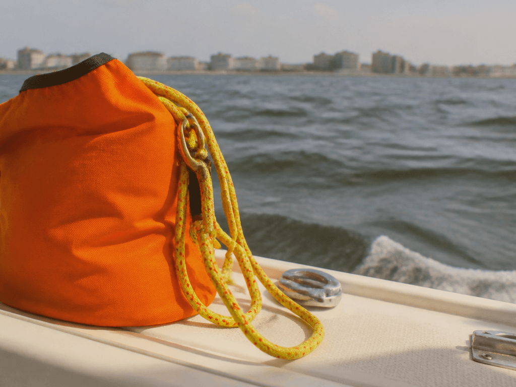 Close-up of an orange throw bag and coiled yellow throw rope ready on a boat deck, Ocean City Maryland across the bay