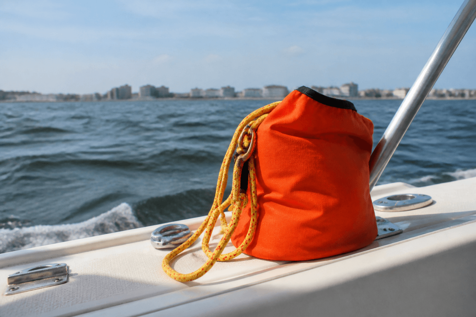 Orange throw bag and yellow rescue rope staged on a boat gunwale with the Ocean City skyline across the water